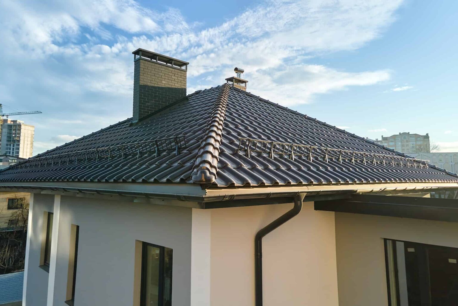 closeup-of-house-roof-top-covered-with-ceramic-shingles-with-gutter-pipes.jpg